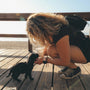 woman in black tank top and black shorts sitting on wooden dock beside black short coated