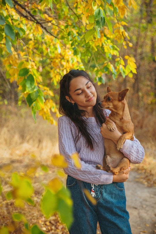 woman in gray long sleeve shirt carrying brown short coated dog during daytime