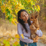 woman in gray long sleeve shirt carrying brown short coated dog during daytime