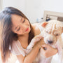woman in white tank top hugging brown and white short coated dog