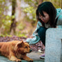 woman in gray jacket hugging brown long coated dog