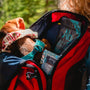 woman in red and black jacket carrying baby in blue jacket