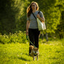 a woman walking a dog in a grassy field