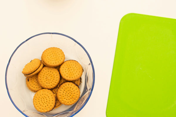 a bowl of crackers next to a green cutting board