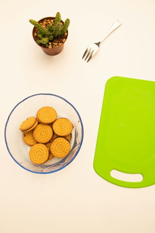 a bowl of crackers next to a green cutting board
