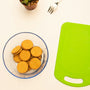 a bowl of crackers next to a green cutting board