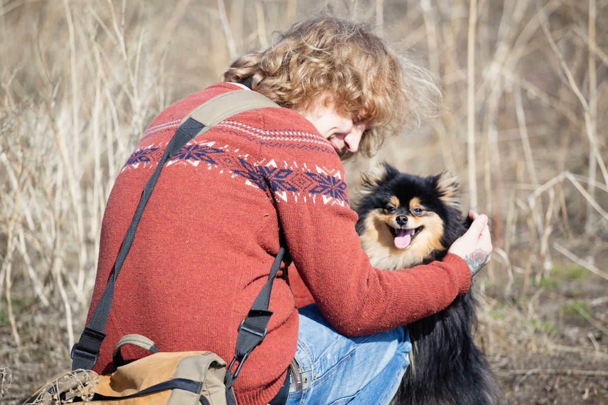 a woman sitting on the ground holding a small dog