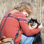 a woman sitting on the ground holding a small dog