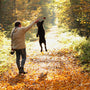 a man walking down a leaf covered road with a dog