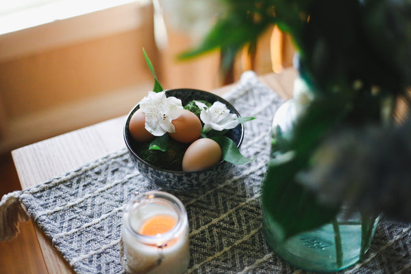 a bowl of eggs sitting on a table next to a candle