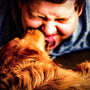 a man laying on a bed kissing a dog