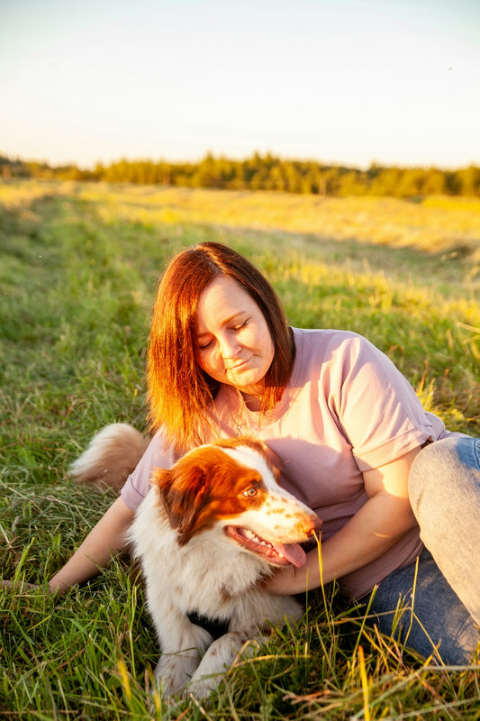 a person sitting in a field with a dog