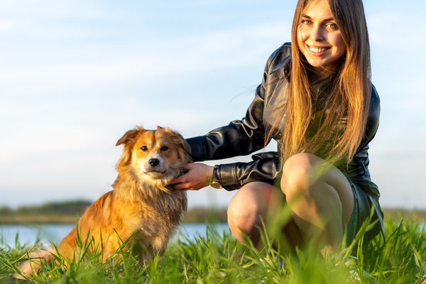 a woman kneeling down next to a brown dog