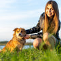 a woman kneeling down next to a brown dog