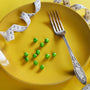 a plate with a fork, measuring tape and green peas