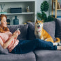 a woman sitting on a couch next to a dog
