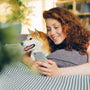a woman laying on a bed with a dog looking at a cell phone