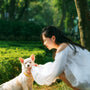 A woman kneeling down next to a white dog