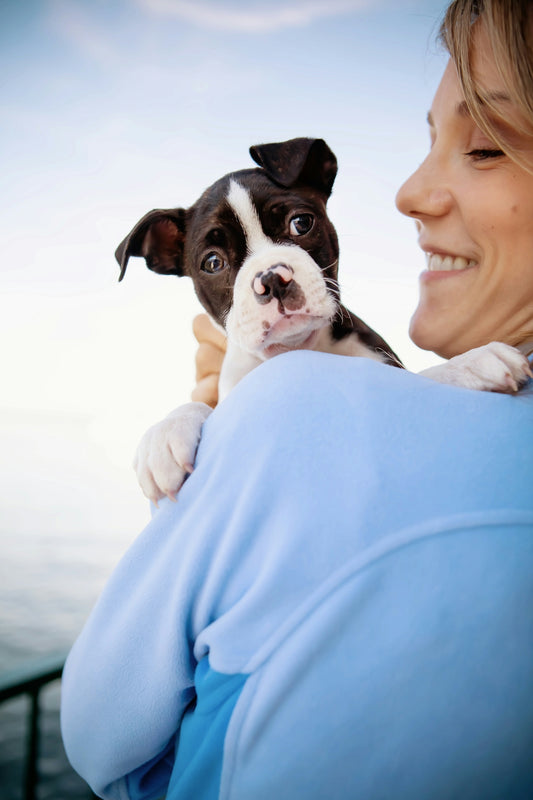 Woman happily holds a cute puppy.