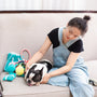 Woman pets a bulldog on a couch with dog toys.