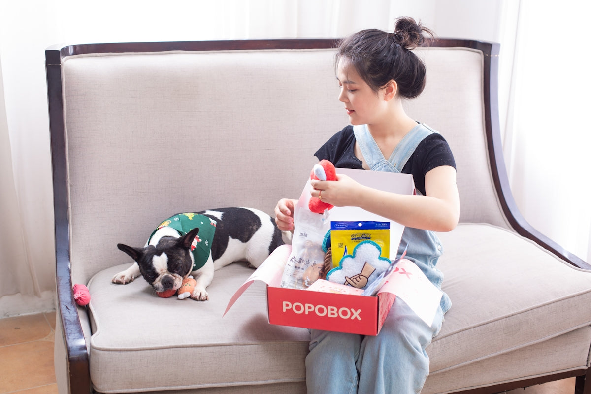 Woman opens a dog box with her dog.