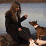 A woman trains her dog beside the water.