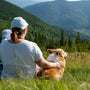 A woman, baby, and dog enjoy a mountain view.