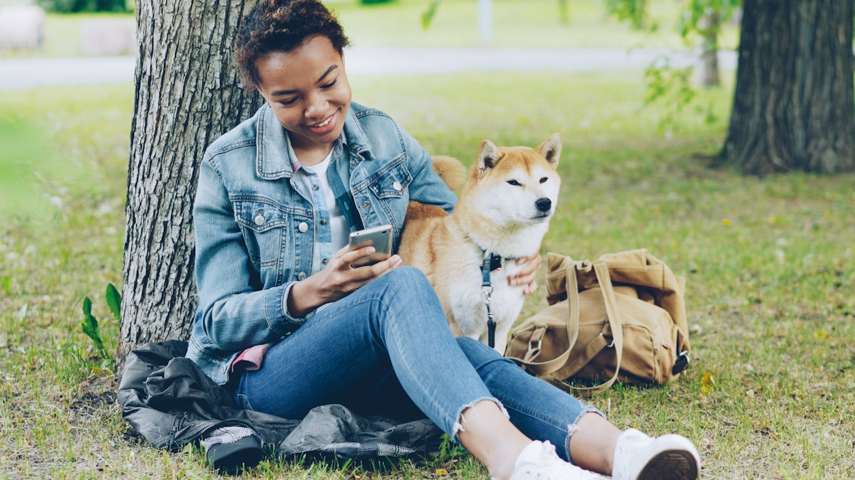 Woman and dog relax under a tree together.
