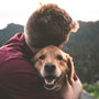 photo of man hugging tan dog