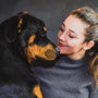 woman in black crew neck shirt hugging black and tan short coat dog