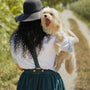 woman in black hat carrying brown long coated small dog