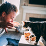 woman in gray sweater holding black and brown cat