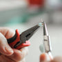 person holding black and red handle stainless steel tool
