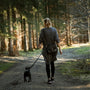 woman in black jacket walking with black labrador retriever on pathway during daytime