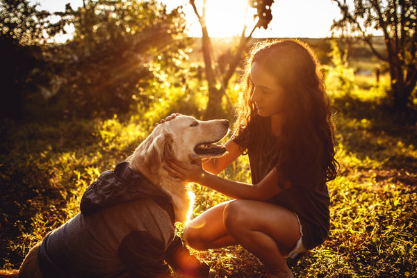 woman in black shirt hugging golden retriever