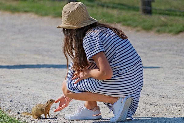 woman in blue and white striped shirt and brown hat sitting on bench