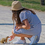 woman in blue and white striped shirt and brown hat sitting on bench