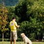 man in yellow shirt and brown shorts holding yellow labrador retriever during daytime