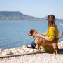 a woman sitting next to a dog on a beach