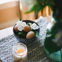 a bowl of eggs sitting on a table next to a candle
