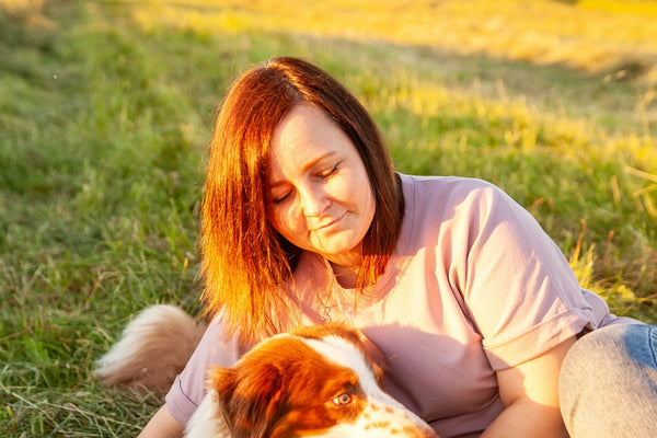 a person sitting in a field with a dog