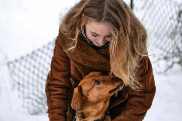 a woman holding a dog in the snow