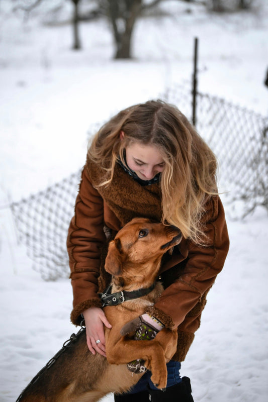 a woman holding a dog in the snow