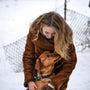 a woman holding a dog in the snow