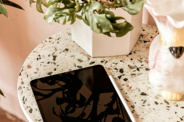 a tablet sitting on a table next to a potted plant