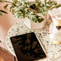 a tablet sitting on a table next to a potted plant