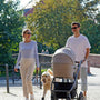 a man and woman walking with a dog in a stroller