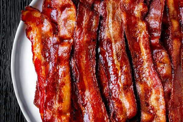a white plate topped with bacon strips on top of a table