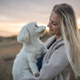 a woman holding a white dog in a field