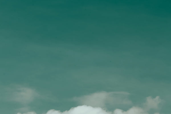 a plane flying in the sky with a cloud in the background
